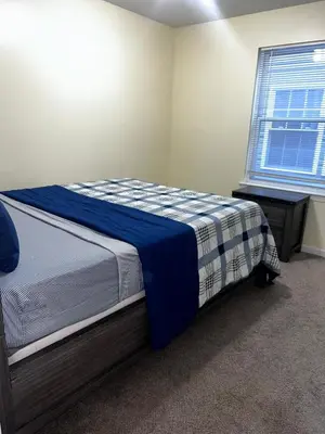 a bedroom with a bed with a blue blanket and a window at 3-Bedroom Apt 5 miles AirPort in Newark