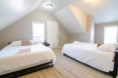 two beds in a attic bedroom with two windows at Near NYC Spacious 4 bedroom 2 and a half bath in North Bergen
