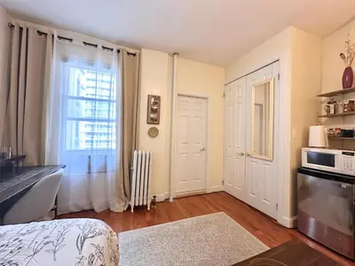 a room with a bed and a window and a kitchen at Urban Luxury Hudson River Suite in New York