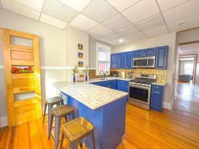 a kitchen with blue cabinets and a counter with stools at The Rustic Home Albany NY - 3 Bedroom Private Second Floor Apartment in Albany