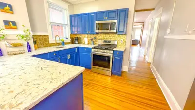 a kitchen with blue cabinets and a wooden floor at The Rustic Home Albany NY - 3 Bedroom Private Second Floor Apartment in Albany