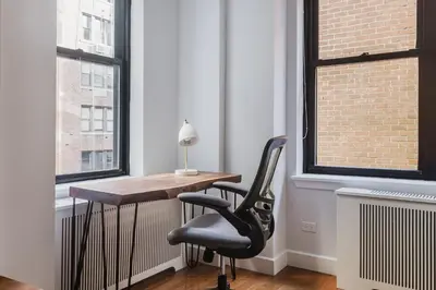 a desk and two chairs in a room with windows at Blueground Sutton Place 1bd apartment NYC-1630 in New York