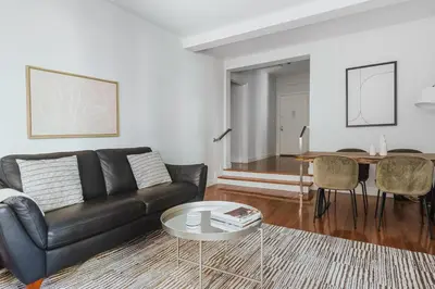 a living room with a black leather couch and a table at Blueground Sutton Place 1bd apartment NYC-1630 in New York