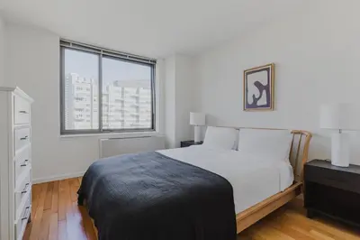 a white bedroom with a bed and a window at Blueground Long Island City 1bd apartment NYC-1612 in New York