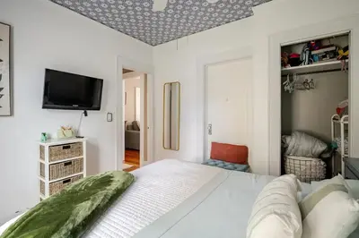 a bedroom with a white bed and a flat screen tv at Gem by the water with firepit & all fenced backyard 2 Bedrooms in Stamford