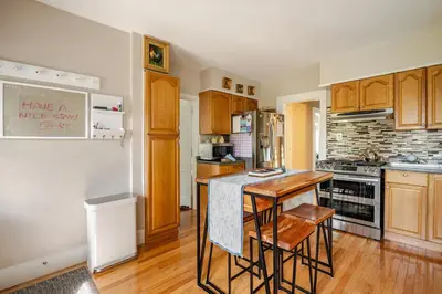 a kitchen with wooden cabinets and a table and chairs at Gem by the water with firepit & all fenced backyard 2 Bedrooms in Stamford