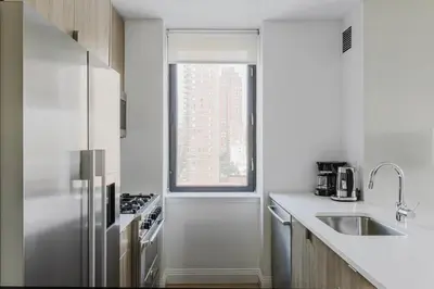 a white kitchen with a sink and a window at Blueground Upper East Side studio apartment NYC-1553 in New York