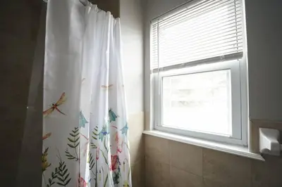 a bathroom with a shower curtain with a window at Newark Liberty Brick House - Private Bedroom 1 in Newark