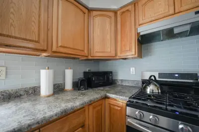 a kitchen with wooden cabinets and a stove top oven at Newark Liberty Brick House - Private Bedroom 3 in Newark
