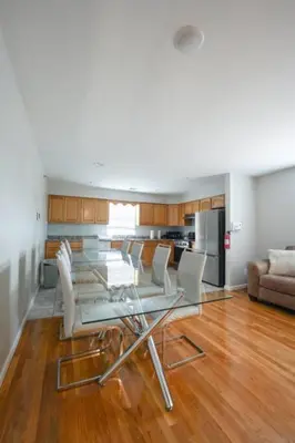 a living room with a glass table and white chairs at Newark Liberty Brick House - Private Bedroom 4 in Newark