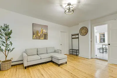 a living room with a couch and a clock on the wall at NYC Area Apartment on Hudson River! in Hastings-on-Hudson