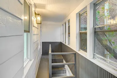 a staircase in a hallway with two windows at NYC Area Apartment on Hudson River! in Hastings-on-Hudson