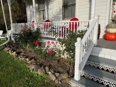 a porch with a white railing and flowers on a house at Victorian Farmhouse in The Catskills in East Meredith