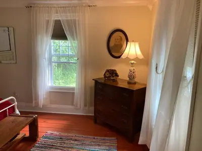 a bedroom with a dresser with a lamp and a window at Victorian Farmhouse in The Catskills in East Meredith