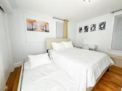 two beds in a room with white walls at Stylish Apartment - Light Rail Access in Bayonne