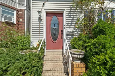 a red door on a white house with a porch at Stylish Apartment - Light Rail Access in Bayonne