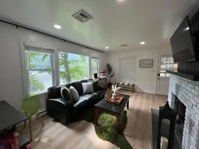 a living room with a black couch and a fireplace at Brown House, Lake, Boat Dock, King Bed, Grill in New Fairfield