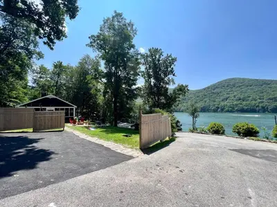 a driveway with a fence next to a lake at Brown House, Lake, Boat Dock, King Bed, Grill in New Fairfield