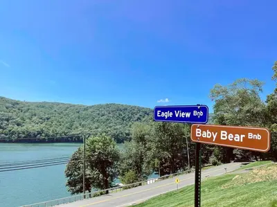 a blue street sign in front of a river at Brown House, Lake, Boat Dock, King Bed, Grill in New Fairfield