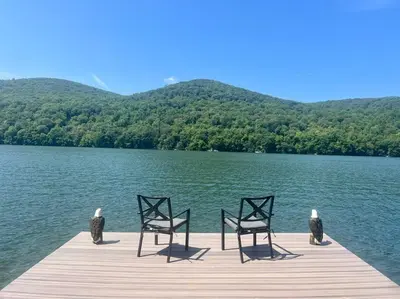 two birds sitting on a dock on a lake at Blue House, King Bed, Grill, Pool Table, Air Hockey, Ping Pong in New Fairfield