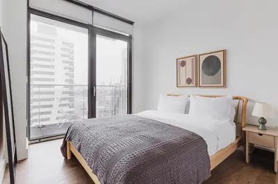 a white bedroom with a bed and a large window at Blueground LIC gym balcony nr MoMA PS1 NYC-1659 in New York