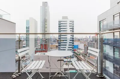 a table and chairs on a balcony with a view of a city at Blueground LIC gym balcony nr MoMA PS1 NYC-1659 in New York