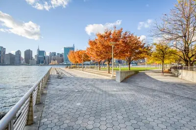 a sidewalk next to a body of water with a city at Blueground LIC gym balcony nr MoMA PS1 NYC-1659 in New York