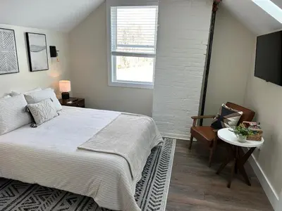 a bedroom with a bed and a chair and a window at The Innwoods - Studio Apartment 1 in Tannersville