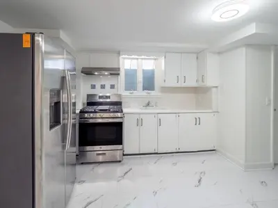 a kitchen with white cabinets and a stainless steel refrigerator at New Canaan's Downtown Retreat in New Canaan