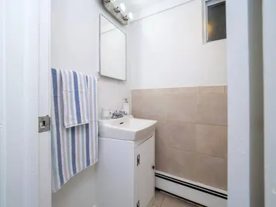 a white bathroom with a sink and a mirror at New Canaan's Downtown Retreat in New Canaan