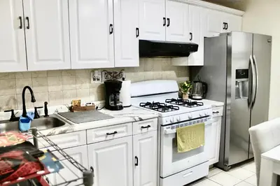 a kitchen with white cabinets and a stainless steel refrigerator at Private Room C West NY, NJ 12 mints from NYCity Times Square in West New York