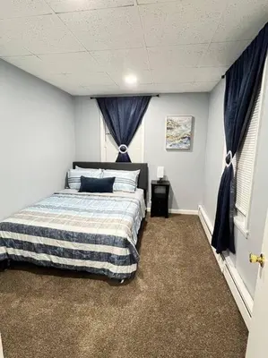 a bedroom with a bed in a room with blue curtains at Criscaris Homes in New Britain