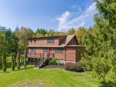 a large house with a staircase in the front yard at New! 3BR Contemporary Log Home in Catskill Mtns in Margaretville
