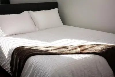 a bed with white sheets and pillows with a blanket at Modern 2BR, Easy access to NYC in Jersey City