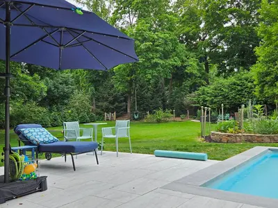a patio with a table and an umbrella next to a pool at Heart Historic Ridgefield Studio WALK to town in Ridgefield