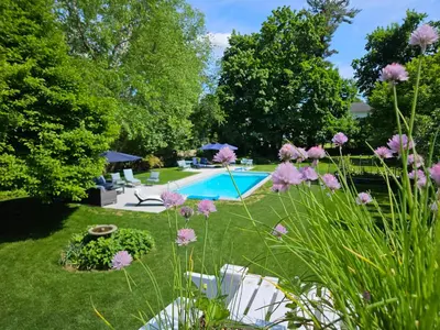 a garden with a swimming pool and purple flowers at Heart Historic Ridgefield Studio WALK to town in Ridgefield