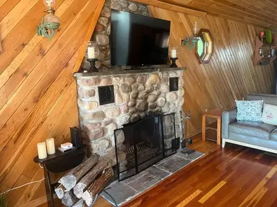 a living room with a stone fireplace with a flat screen tv at Lake Moraine Home #7 Near Colgate University in Hamilton