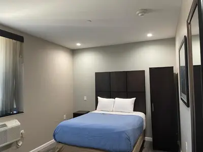 a bedroom with a large bed with blue sheets and white pillows at Voyage Hotel in Long Island City