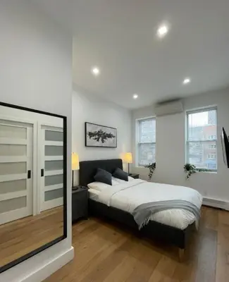 a bedroom with a bed and a large window at Stunning Family Style Duplex in New York