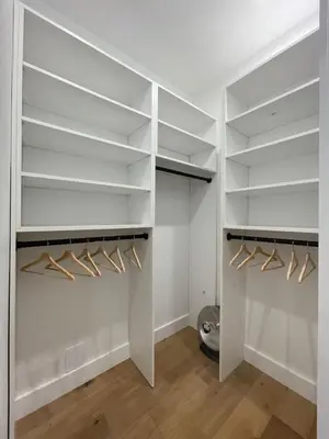 a walk in closet with white shelves and wooden floors at Stunning Family Style Duplex in New York