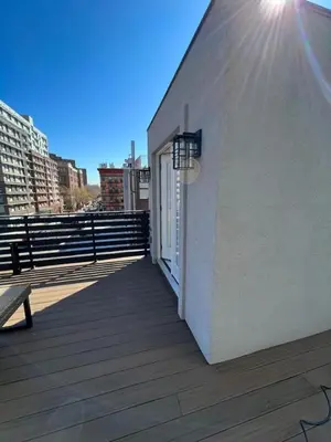 a white building with a window and a bench on a deck at Stunning Family Style Duplex in New York