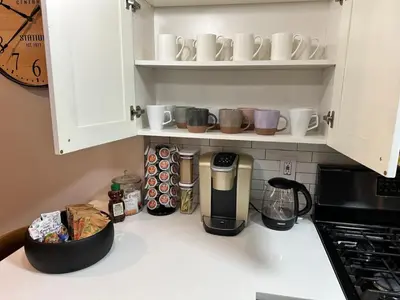 a kitchen counter with a coffee maker and cups on shelves at Charming Central Park Townhome in New York