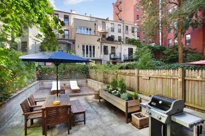 a patio with a table with an umbrella and a grill at Charming Central Park Townhome in New York