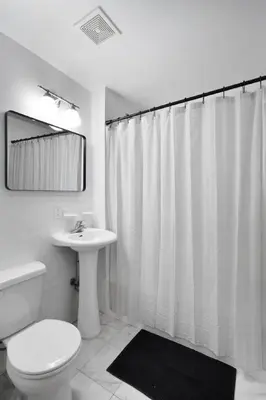 a bathroom with a toilet sink and a shower curtain at Charming Central Park Townhome in New York