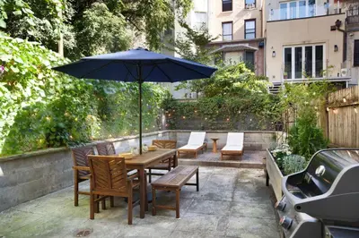 a patio with a table and chairs and an umbrella at Charming Central Park Townhome in New York