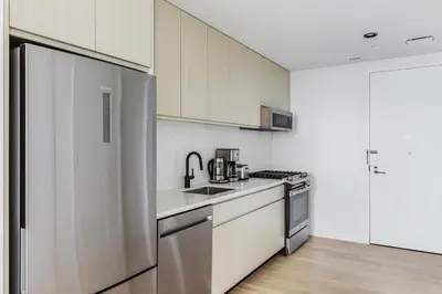 a kitchen with white cabinets and a stainless steel refrigerator at Blueground Downtown BK gym wd nr BAM NYC-1685 in Brooklyn