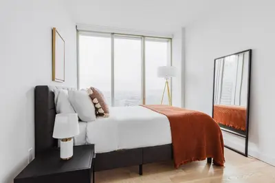 a white bedroom with a bed and a large window at Blueground Downtown BK gym wd nr BAM NYC-1685 in Brooklyn