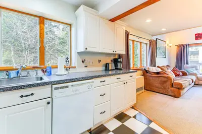 a kitchen with white cabinets and a living room at Walk to Mt Snow Cozy West Dover Condo in West Dover