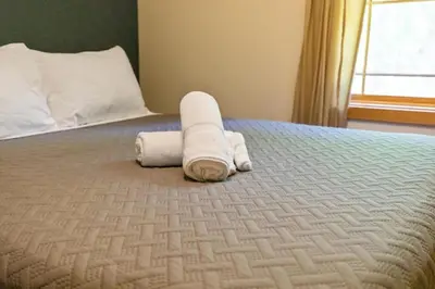 a bed with two rolled up towels on it at Woodland Cabin Getaway in Greentown
