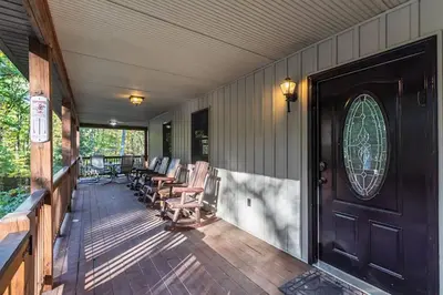 a porch with rocking chairs and a wooden door at Woodland Cabin Getaway in Greentown
